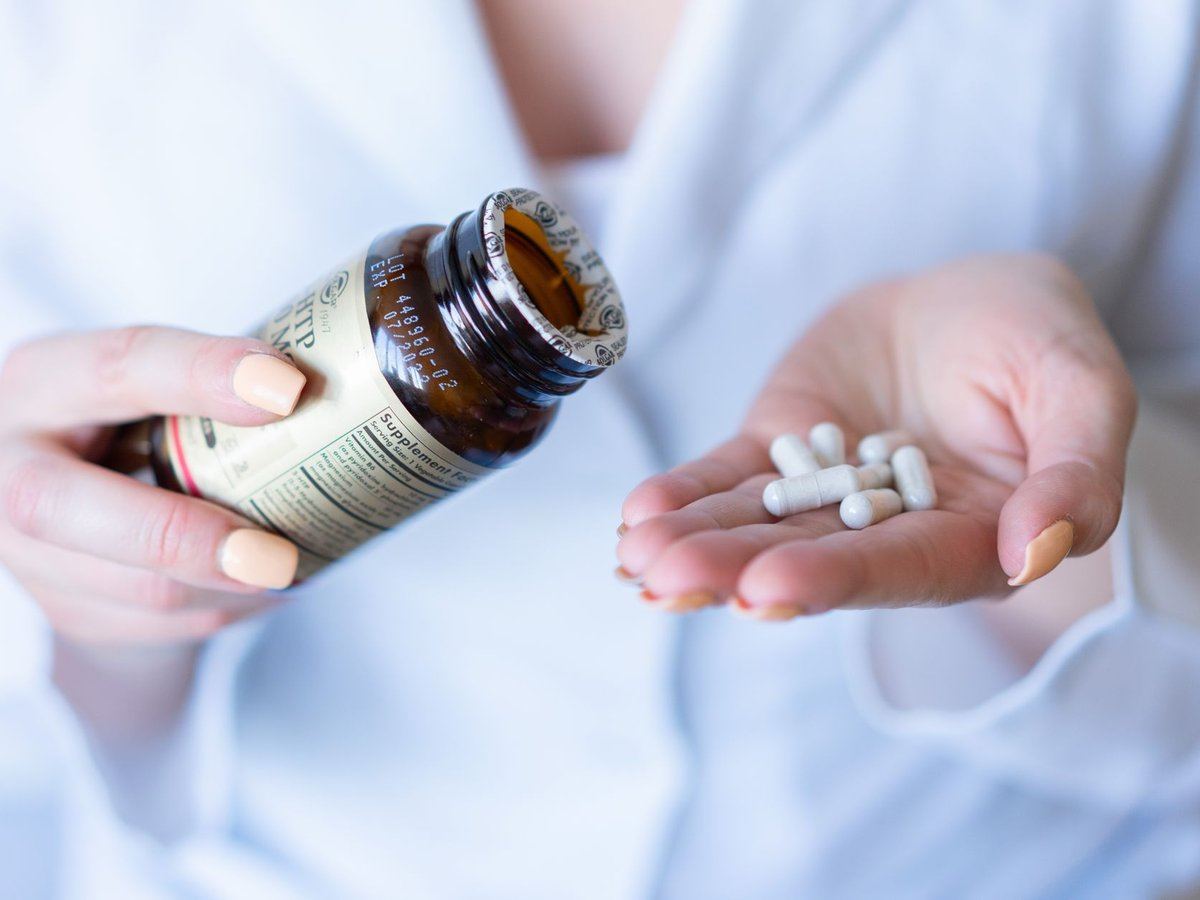 Supplement capsules poured from a bottle into a hand